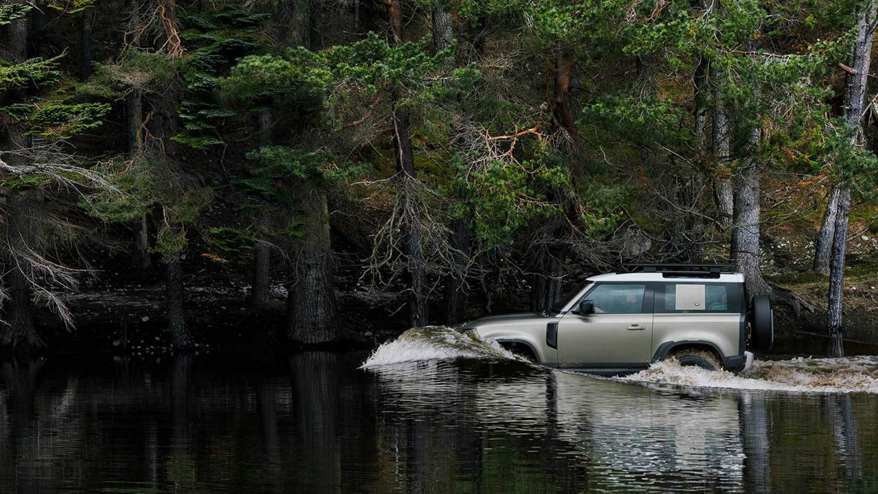 Land Rover Defender driving through a lake
