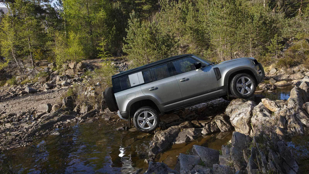 Land Rover Defender parked on a rock into river