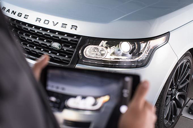 person takes a picture with a tablet of a range rover vehicle