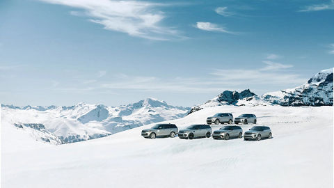 Land Rover vehicles parked at snowy mountain