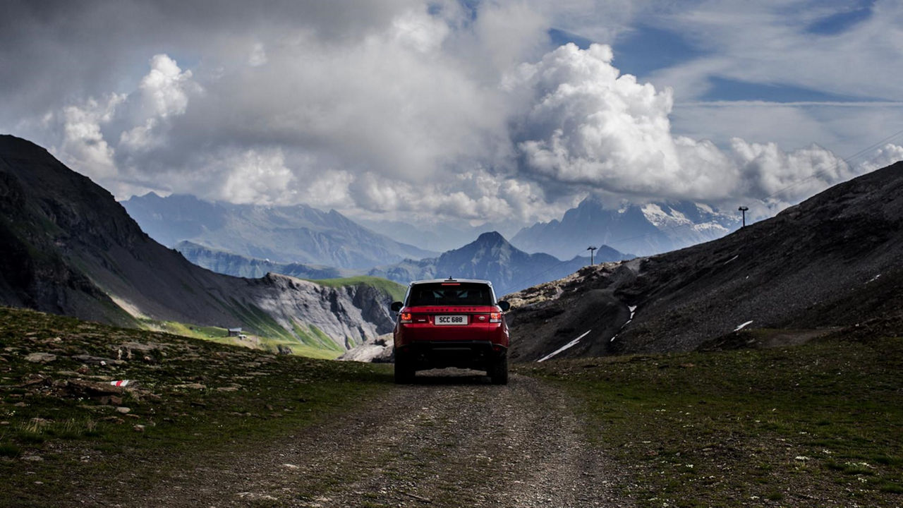 Range Rover in red back view mountain landscape