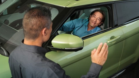 Person greets another one in a green Range Rover