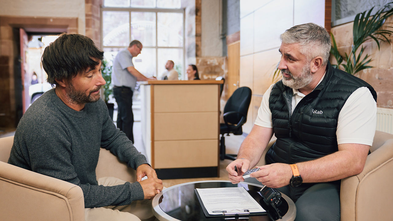 Two men sitting in an office , having a conversation.