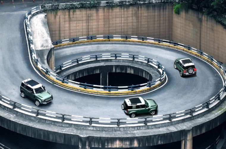 Land Rover Defenders driving down winding road