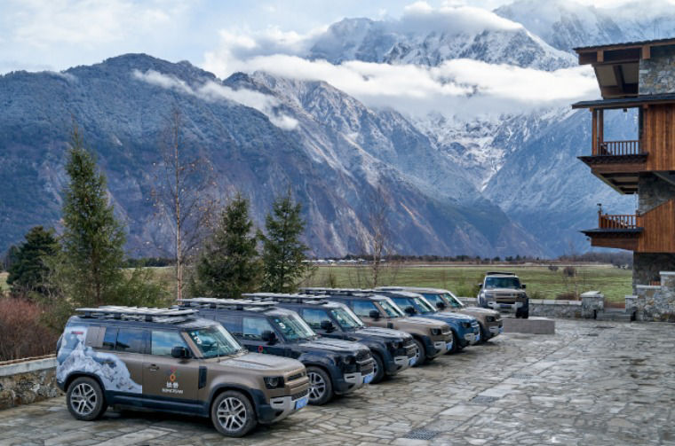 Land Rover Defender vehicles parked in mountain landscape