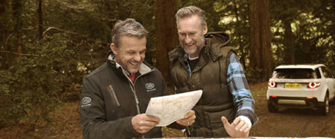 Two men by a Land Rover vehicle in forest