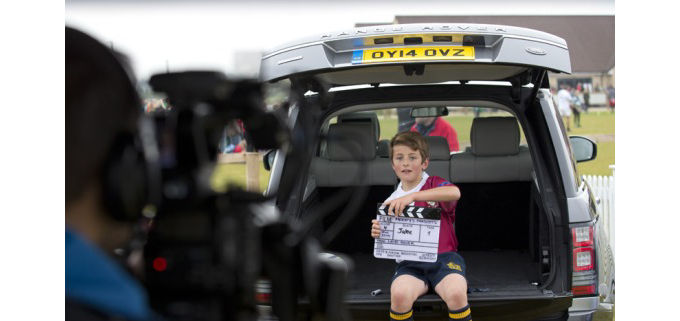 Child holding clapperboard sitting in the back of a Range Rover