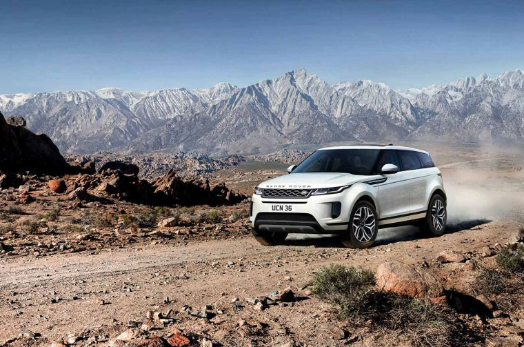 Range Rover Evoque driving on dirt road in mountain landscape