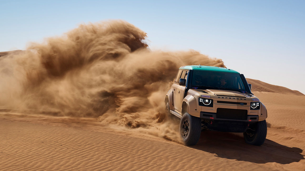 Off-road DEFENDER speeding through desert dunes.